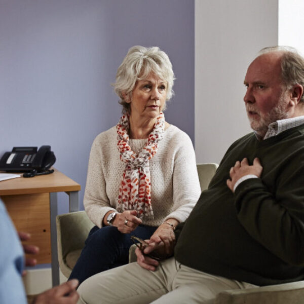 Couple at medical appointment, woman comforting the man who's holding his chest