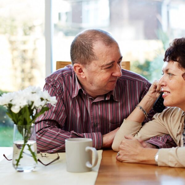 A couple sit at a table holding hands as the talk to each other.