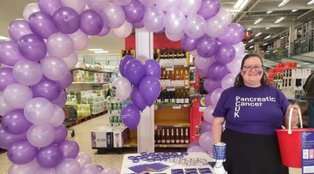 Volunteer smiling with collection bucket raising awareness for PCUK