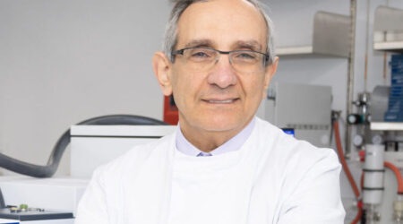 Professor George Hanna standing in a lab wearing a white lab coat with his arms crossed looking at camera