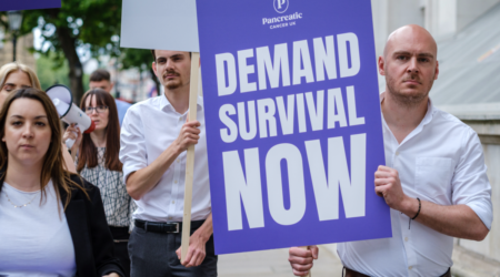 men and women walking down the street with signs one reading demand survival now