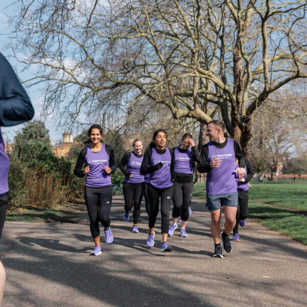 man running closely to screen while a group of runners hangs back to and chat with each other