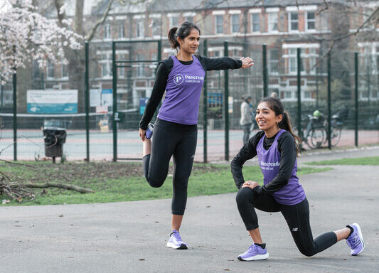 Two women stretching their legs in a park/playground