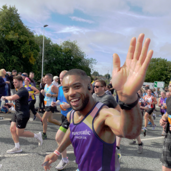 A person wearing the pancreatic cancer top running in a race, waving at the camera