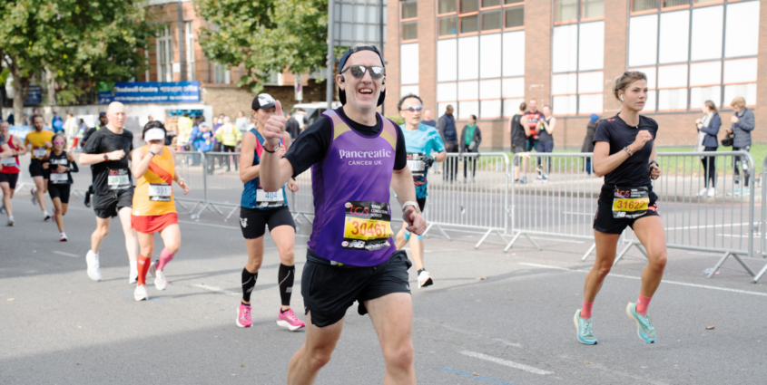 Male runner smiling at the camera and giving thumbs up while running the TCS London Marathon