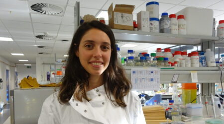 Female researcher, Dr Bea Salvador stands in her lab smiling