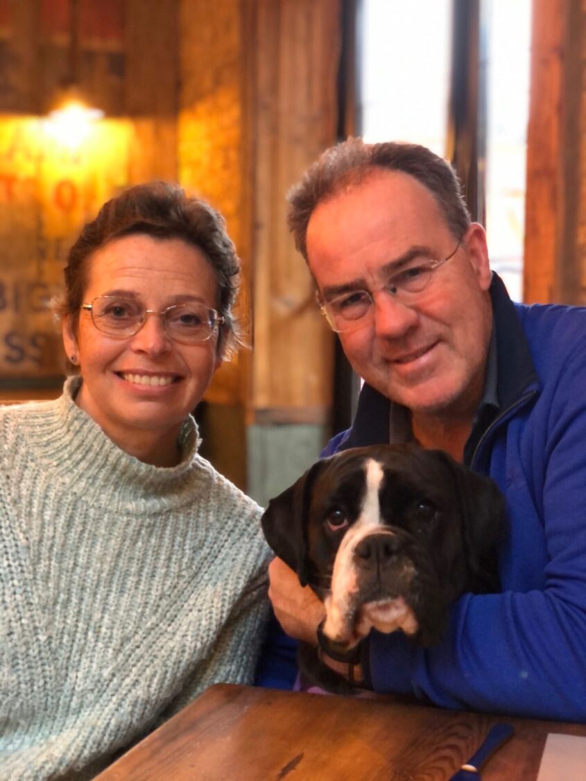 Man and woman with boxer type dog all looking at camera