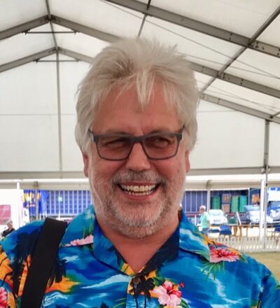 Man wearing brightly coloured shirt standing in a marquee, smiling