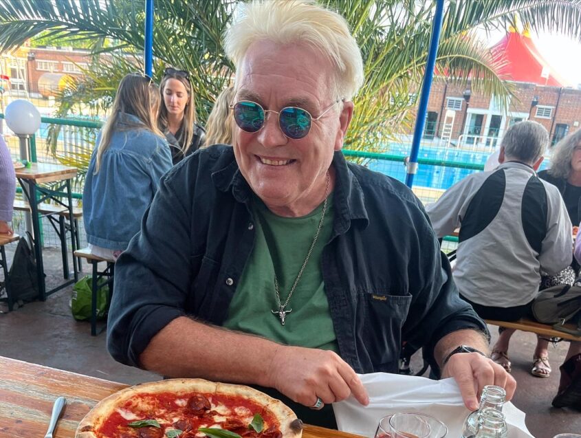 Man in outside restaurant with pizza in front of him