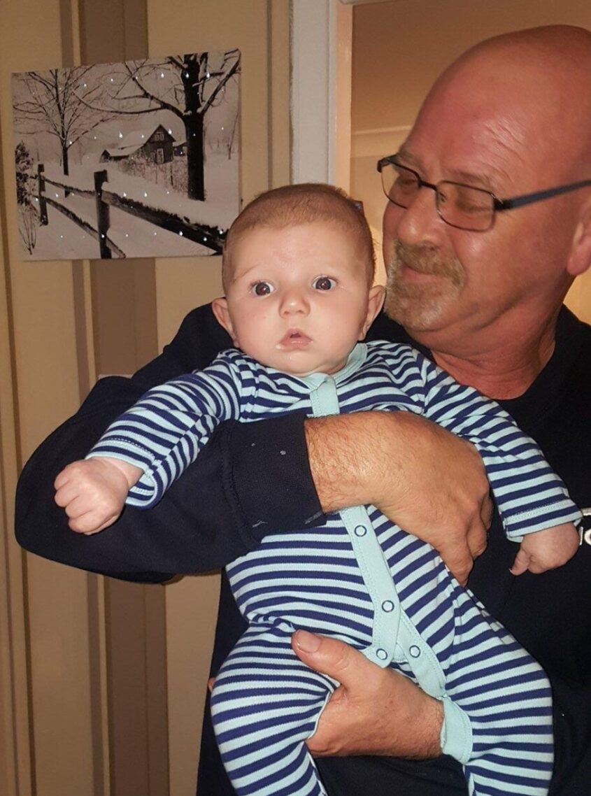 Man holding young baby inside a house