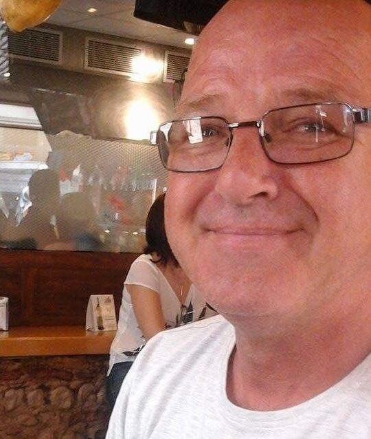 Man sitting in restaurant, smiling to camera