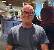 Man sitting at table in restaurant smiling to camera